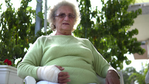 年长的老年妇女受伤手折断手臂坐着说话的肖像13秒视频