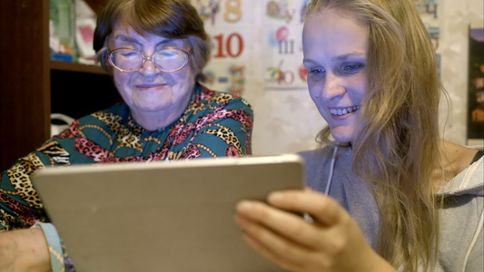 女青年年青和年长女性在墙上看照片视频