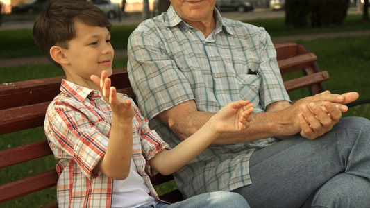 高大男人和孙子一起在板凳上玩视频