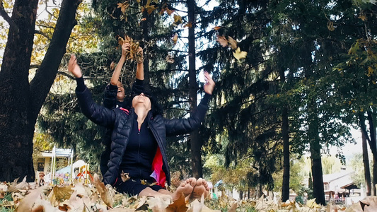 赤脚母亲和她的儿子坐在秋天公园玩得开心女人在空中扔视频