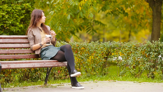秋天概念美丽的女人在秋季公园喝咖啡在秋天的树叶下视频