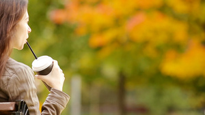 秋天概念美丽的女人在秋季公园喝咖啡在秋天的树叶下13秒视频