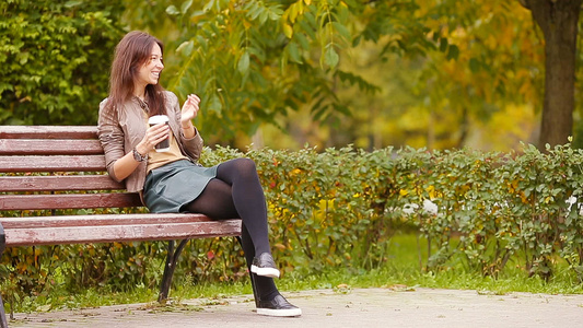 秋天概念美丽的女人在秋季公园喝咖啡在秋天的树叶下视频