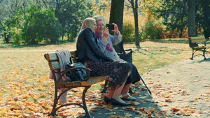 年轻女性和祖母在公园的智能手机上观看某事的放大镜头12秒视频
