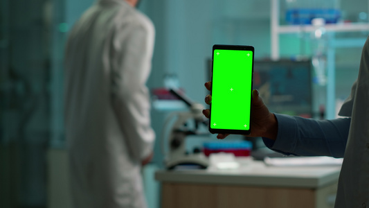 密闭的化学家手握着绿屏手机视频