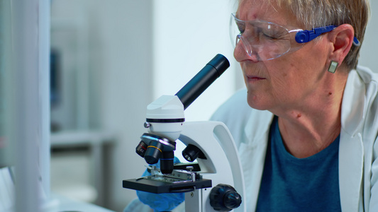 近距离观察显微镜下样本的女研究科学家在视频