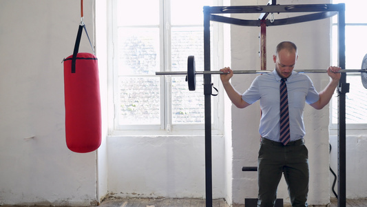 穿着西装的男人在做深蹲商人在健身房里用杠铃锻炼成功视频