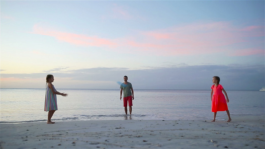 快乐的家庭在日落的海滩玩飞盘游戏视频