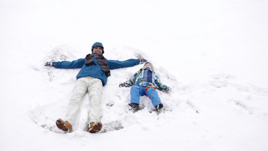 父亲和儿子在冬天做雪天使视频