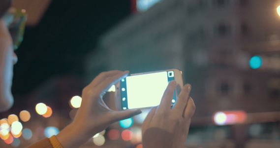 使用手机拍摄晚上城市照片的女孩视频