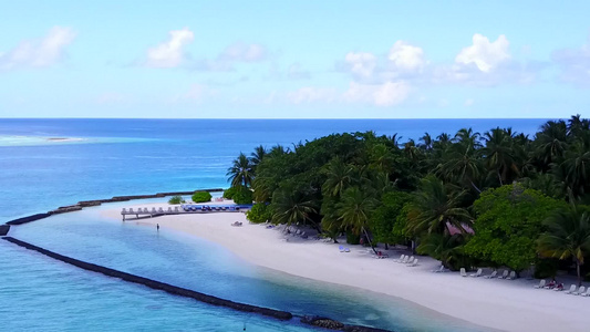 观赏白沙背景的绿绿水在海滩上航行的天堂度假胜地风景视频