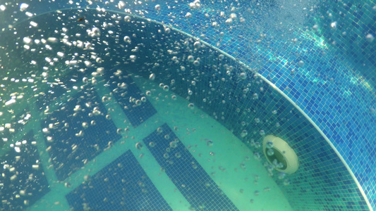在热温泉水池中有蓝色瓷砖的气泡漂浮在水下视频