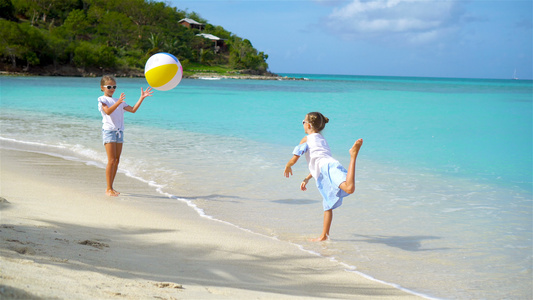 可爱的小女孩玩球在海滩上玩球视频