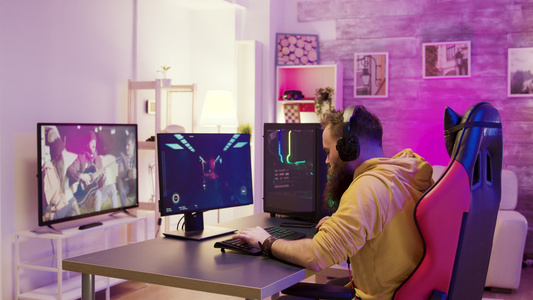 成功的男子在一个有丰富多彩的尼恩的房间在网上玩电子游戏视频