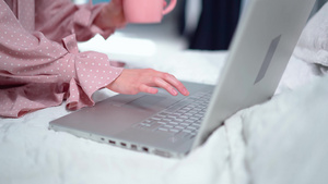 穿着粉红色裙子坐在床上用笔记本电脑工作57秒视频
