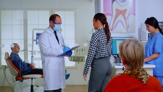 在剪贴板上作笔记的妇女接受问讯的牙医医生视频
