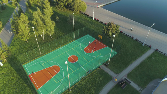 人们在绿色城市公园的球场上打篮球空中最高视线无人机视频