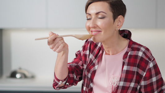 一个美丽的年轻女子在家里准备蔬菜汤的画像使用长木勺视频