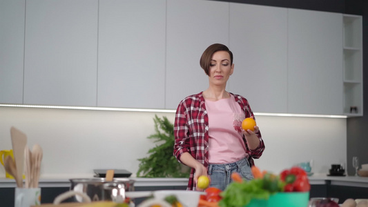快乐的妈妈手里拿着新鲜的黄色番茄和橘子穿着格子衬衫视频