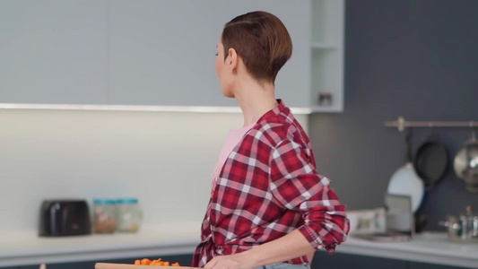 迷人的微笑女人用长木勺品尝站在现代厨房里的熟食在家视频