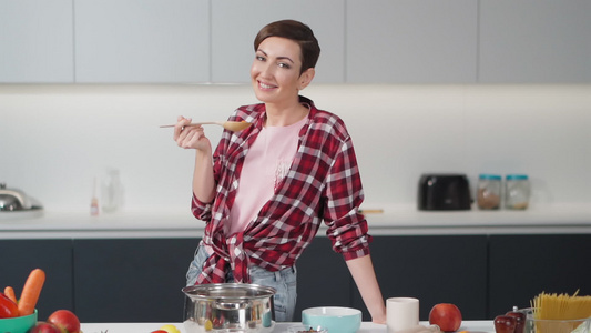 性感的家庭主妇留着短发型在现代厨房里拿着一把长木勺视频