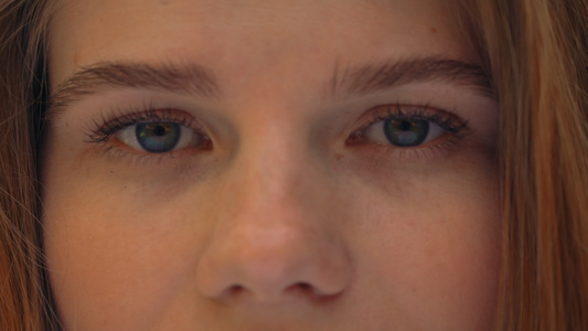 女性蓝眼睛的肖像在镜头上观看视频