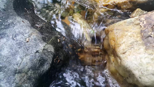 紧闭地看见水流的流光水从石头之间掉落而出流入石块之间视频