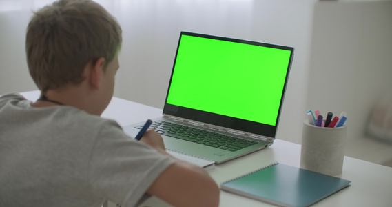 男孩正在通过互联网绘画和观看卡通片假期在家使用笔记本电脑视频