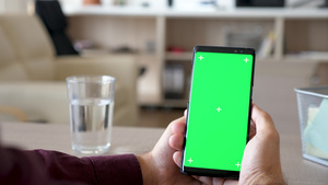 男性手握智能手机的亮光镜头用绿色屏幕15秒视频