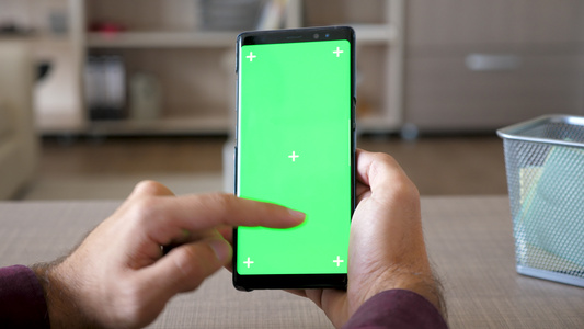 男人拿着智能手机用绿色屏幕染色体装扮起来视频