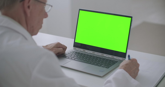 诊所工作治疗师桌上带绿屏的笔记本在线医生预约概念视频