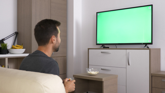 男人在大等离子电视上的绿色模拟屏幕前在控制台玩电子游戏视频