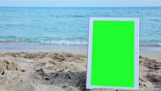 沙滩上有绿色屏幕的平板电脑视频