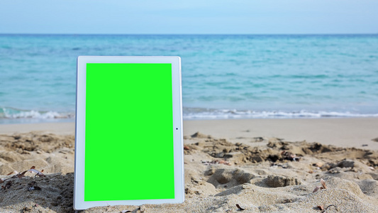 沙滩上有绿色屏幕的平板电脑视频