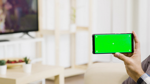 手持绿色屏幕电话在明亮和光亮的生活空间14秒视频