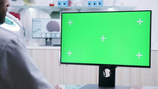 在绿色屏幕模拟计算机上工作的医生的肩部镜头上的静态视频