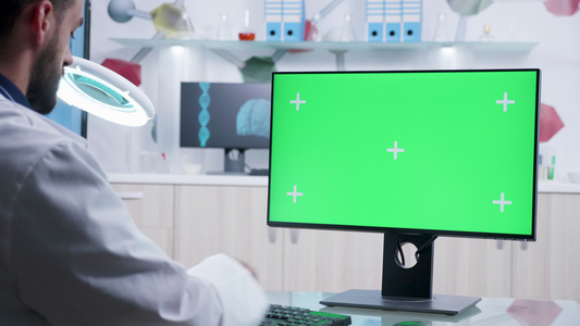 以绿色屏幕模拟计算机操作的医生拍摄的缩放镜头视频