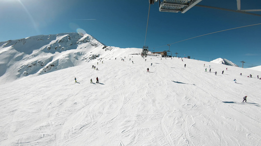 从滑雪升起的第一视角空中看到斜坡和远雪覆盖山峰的滑雪者视频