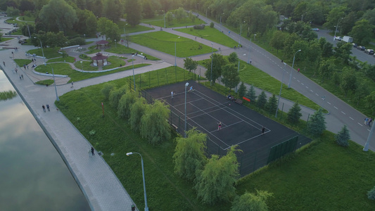 人们在人行道上行走空中观察在绿色城市公园的球场上玩视频