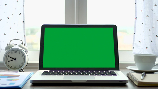 4k手提笔记本电脑在窗户附近的工作办公桌上安装绿色视频