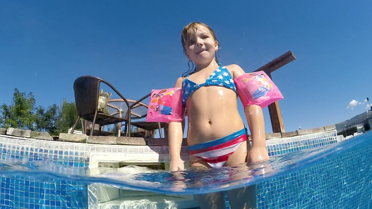 手带的可爱女孩在温泉中心游泳池微笑到相机半水下风景视频