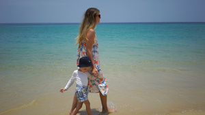 母亲和儿子徒步沿着海边的海滩行走16秒视频