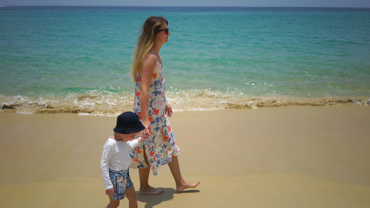 母亲和儿子徒步沿着海边的海滩行走视频