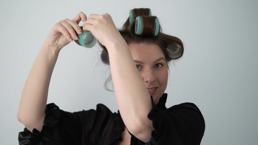 女孩在头发上用卷发做发型穿浴袍内衣的年轻女人视频