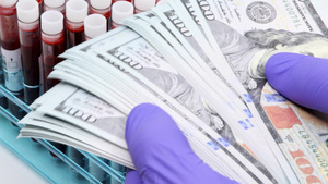 用手术手套将一大堆美元钞票放在试管架上的医生手特写13秒视频