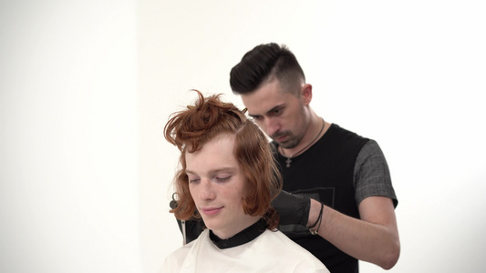 理发师对一个长着红头发的年轻人理发视频