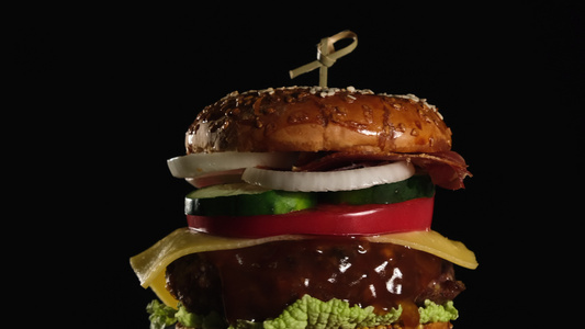 芝士汉堡加西红柿洋葱烧烤小菜和芝麻面包放在一个旧木制视频