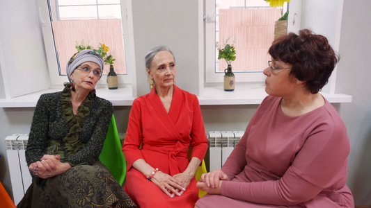 老年妇女坐在养恤金领取者俱乐部里讨论朋友会议并聊天视频