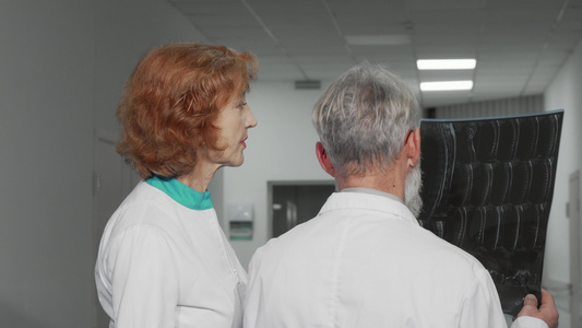 两名年长医生的后视镜头一起检查MRI扫描视频