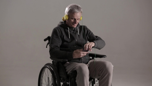 在轮椅上穿便衣的男残疾人工作室拍摄视频